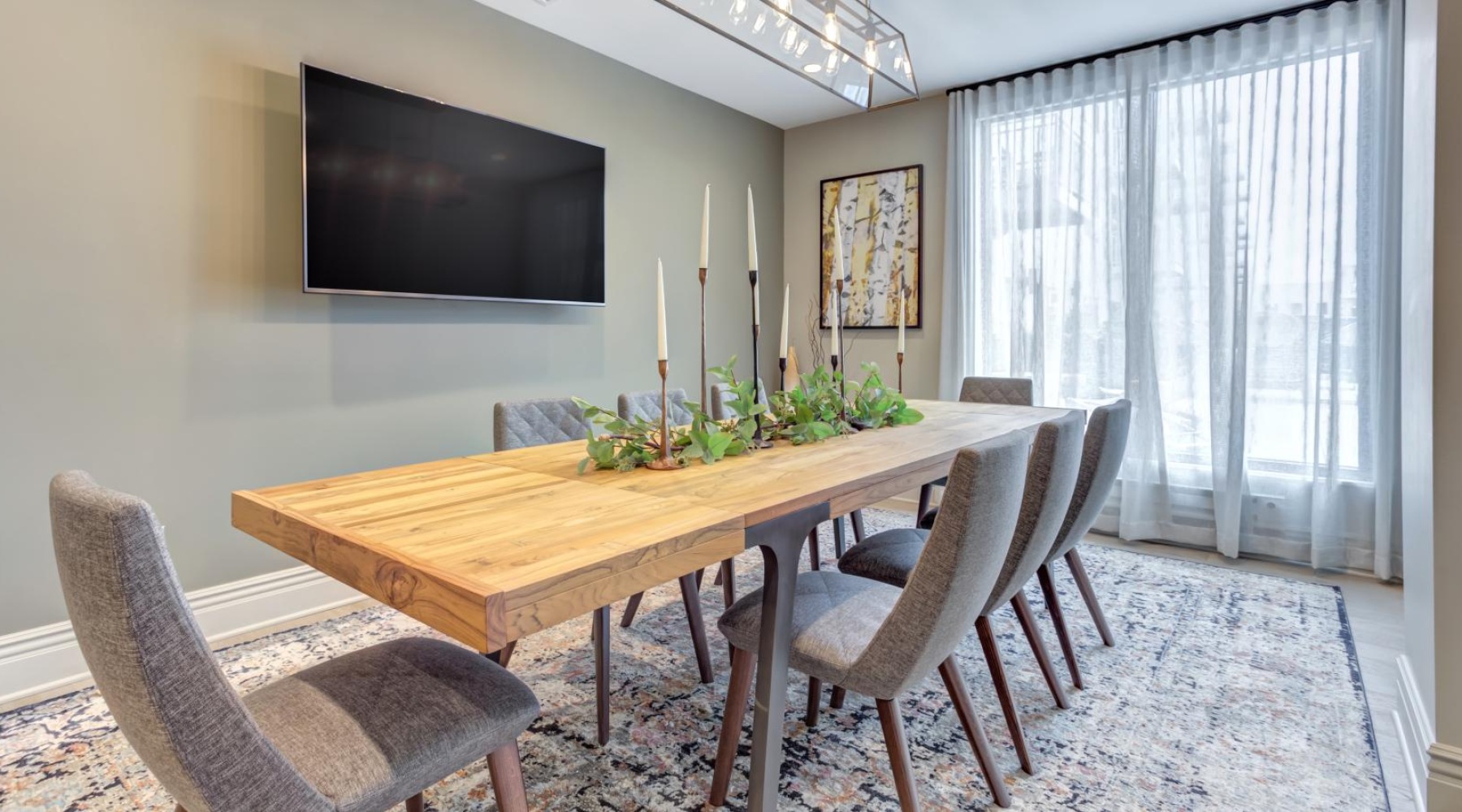 a dining room table with chairs and a tv above it